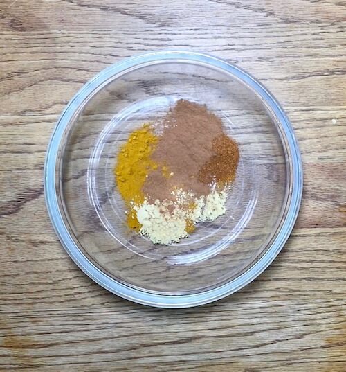 A medium glass bowl with turmeric, mustard seed, cayenne chili pepper, and cinnamon | The Radiant Root