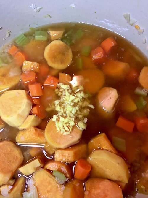 Sweet Potatoes, onion, celery in a pot with vegetable broth and grated ginger|Ginger Sweet Potato Soup | The Radiant Root