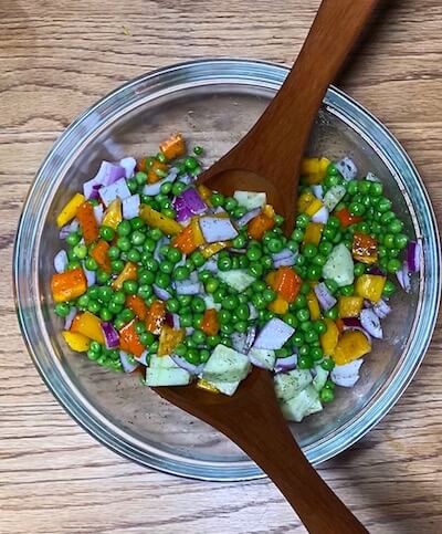 Pea salad with red onion, cucumber, yellow and orange bell pepper in a wildtree dill dip dressing (EVOO and apple cider vinegar) tossed together in a glass bowl with brown wooden salad fork and spoon Healthy Pea Salad |The Radiant Root