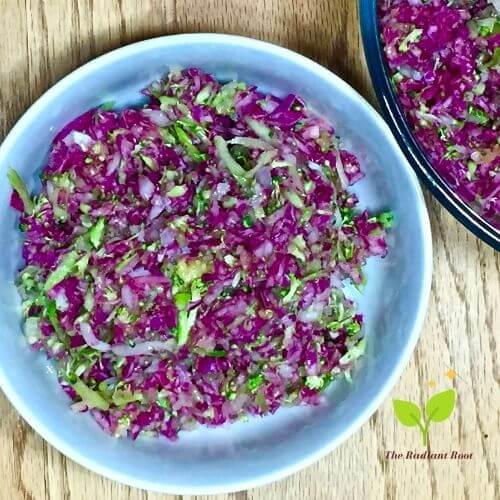 Red Cabbage Broccoli Slaw with Mango in a White bowl on a wooden table | The Radiant Root