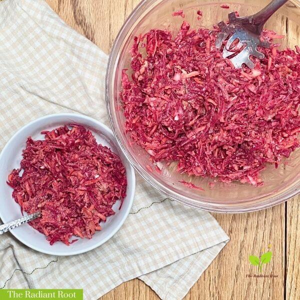 Shredded beet and carrot salad with avocado lime dressing in a white bowl on a wooden table | The Radiant Root