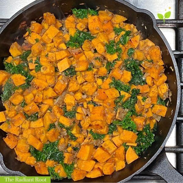 Cast Iron Skillet with Cooked Sweet Potatoes, Diced White Onion,Garlic, Cinnamon, and Kale | Kale Sweet Potato Hash | The Radiant Root