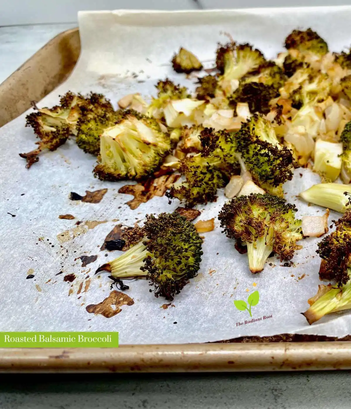 A close of up finished recipe of the balsamic roasted broccoli on a baking sheet with the words "The Radiant Root" in white font with green outline | Roasted Balsamic Broccoli | The Radian Root