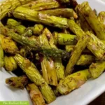 A white dish overflowing with air fried asparagus bite-size pieces | fried asparagus recipe | The Radiant Root