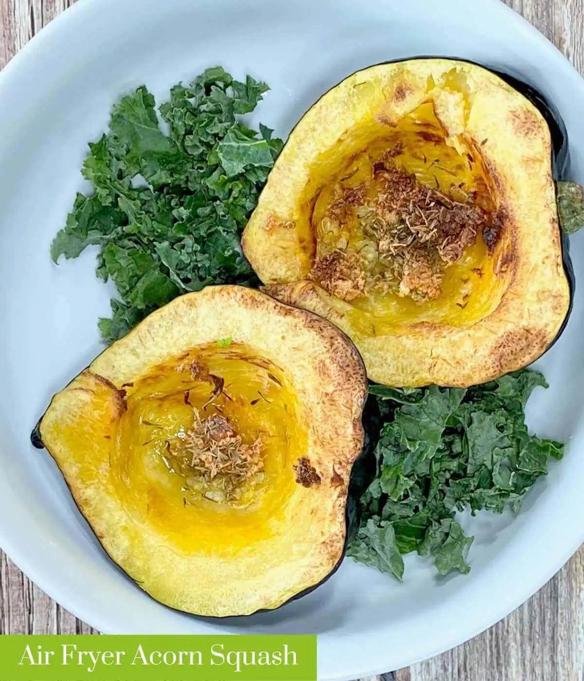 acorn squash air fryer with olive oil, garlic, and thyme in a white bowl surrounded by a bed of kale on a brown wooden table | The Radiant Root