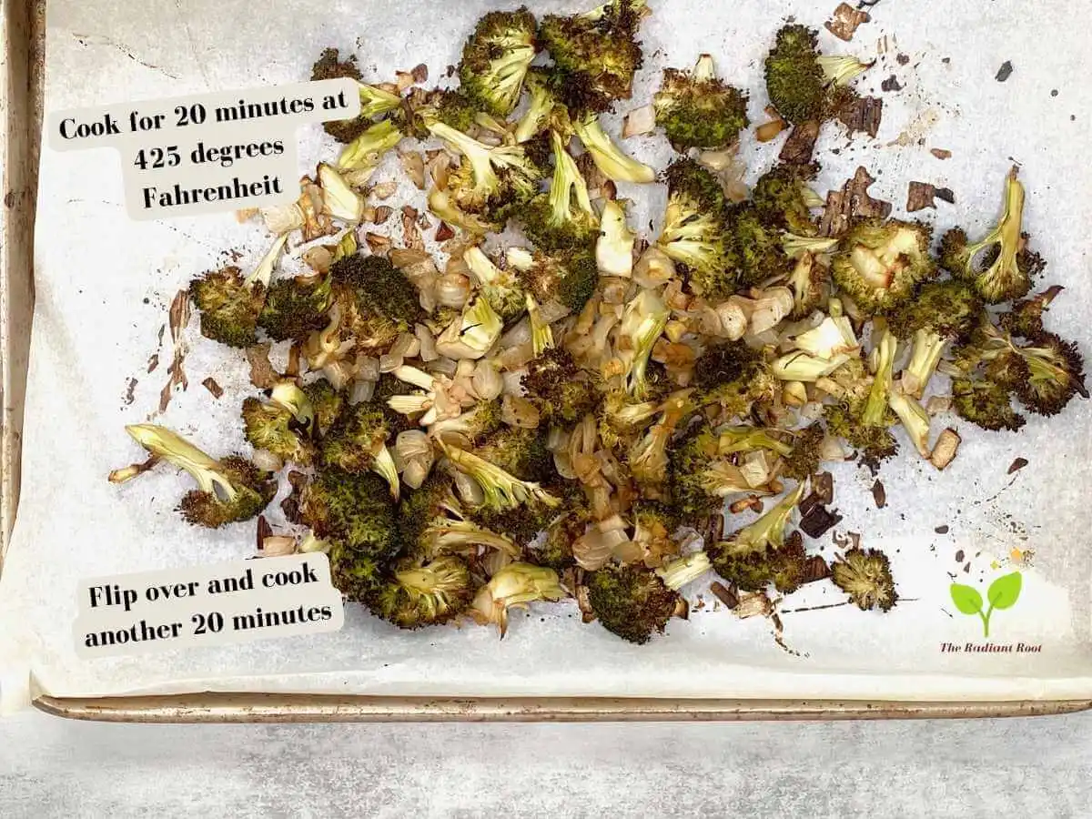 Roasted Balsamic Broccoli Instruction Photo 10 of 11: There is a copper colored baking sheet lined with parchment paper on top of grey slate table showing the cooked broccoli, garlic, onion, and balsamic vinegar mixture. Above to the left it reads “Cook for 20 minutes at 425 degrees Fahrenheit.” And below to the left it reads “Flip over and cook for another 20 minutes.” | how to make roaste broccoli | The Radiant Root