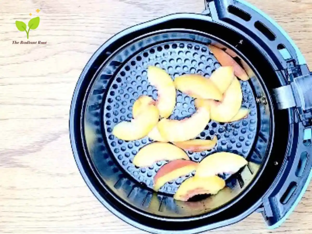 Air Fryer Peaches recipe ingredient step photo 1 of 3 with an air fryer basked with a peach raw and sliced laid out in the air fryer basket | The Radiant Root