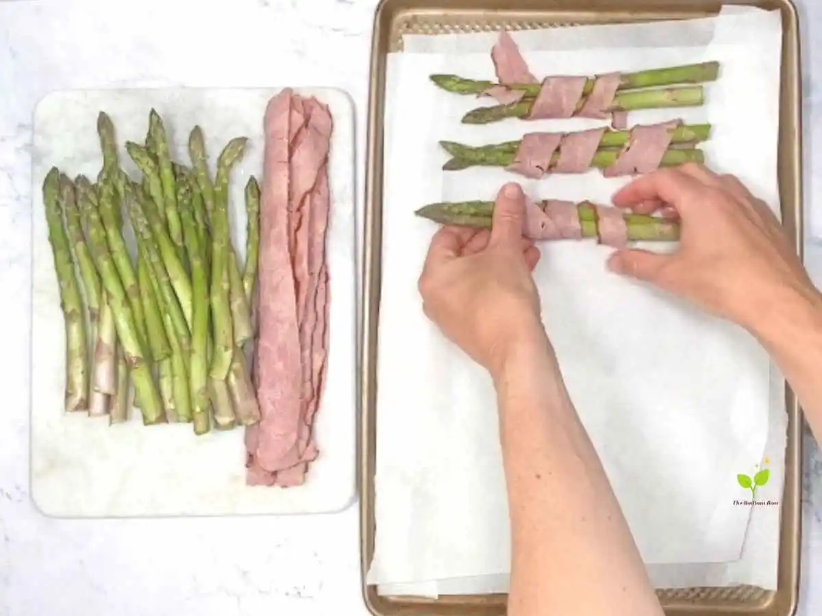 Instructions Photo 4 of 6 for Asparagus Wrapped In turkey BaconHands placing asparagus spears wrapped with turkey bacon on a baking sheet with parchment paper | how to cook asparagus. | The Radiant Root