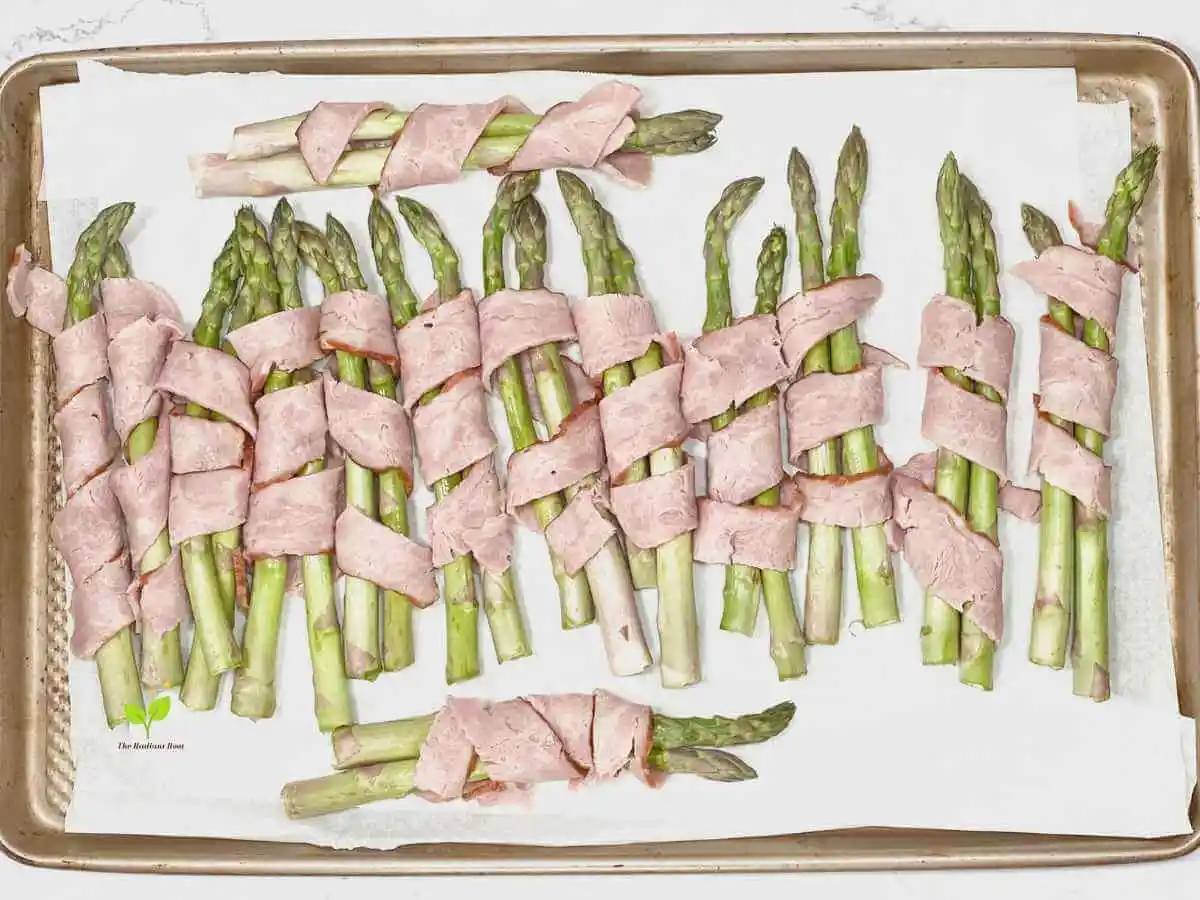 Instructions Photo 5 of 6 for Asparagus Wrapped In turkey Bacon: A baking sheet with parchment paper lined with asparagus wrapped in turkey bacon raw before cooking |how to eat asparagus | The Radiant Root