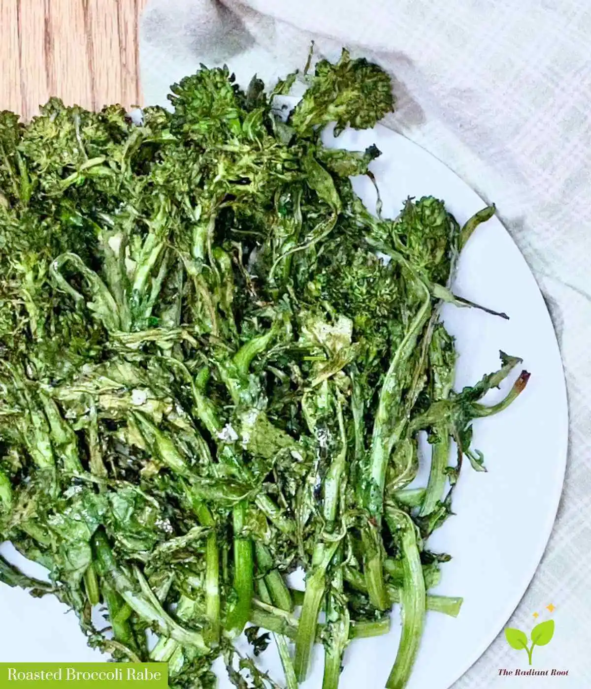 Broccoli rabe on a white plate with a beige kitchen towel on a wooden table | Roasted Broccoli Rabe | The Radiant Root