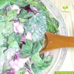 Cucumber Beetroot Salad WP recipe maker image: A close up of a wooden table with a large salad bowl containing the beet and cucumber salad dressed tossed in the lemon tahini dressing with a salad spoon sitting in the bowl. | salad with beetroot | The Radiant Root