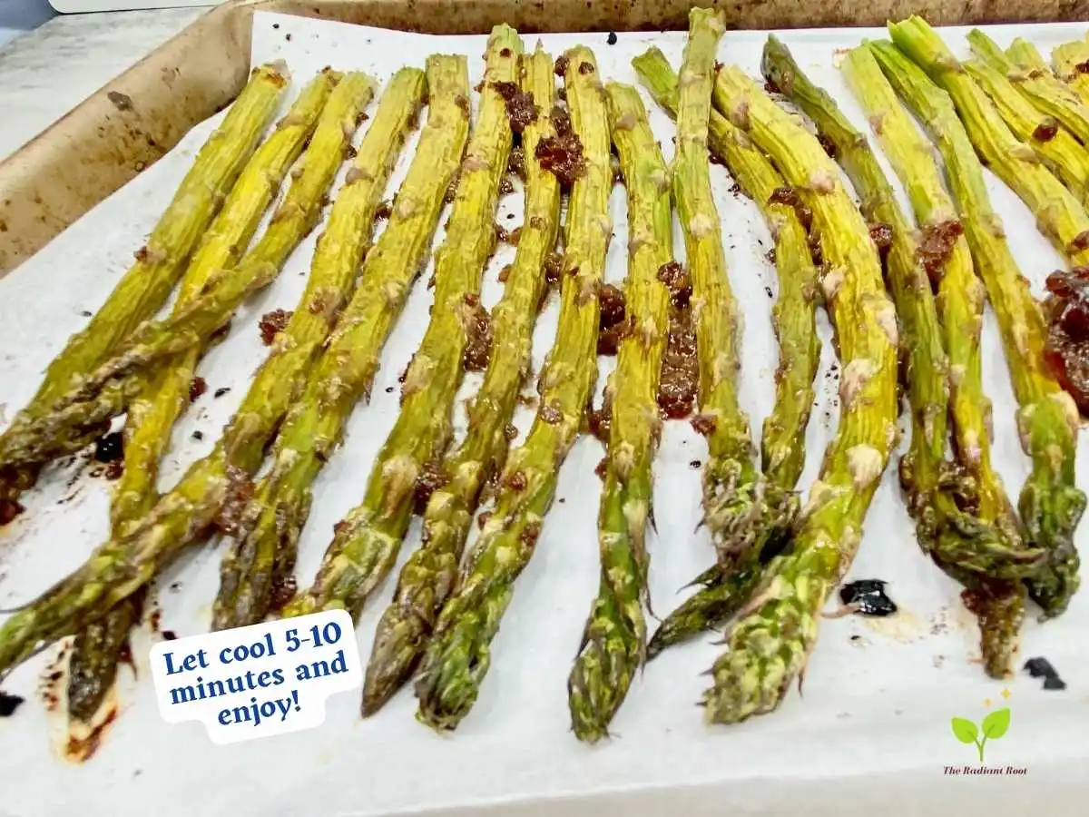 Balsamic glazed asparagus recipe instruction photo 10 of 10 : A grey marble table top containing a close up of a lined baking sheet containing of finished balsamic glazed asparagus. It reads “let cool 5-10 minutes and enjoy!” | nutrition facts for balsamic vinegar | The Radiant Root