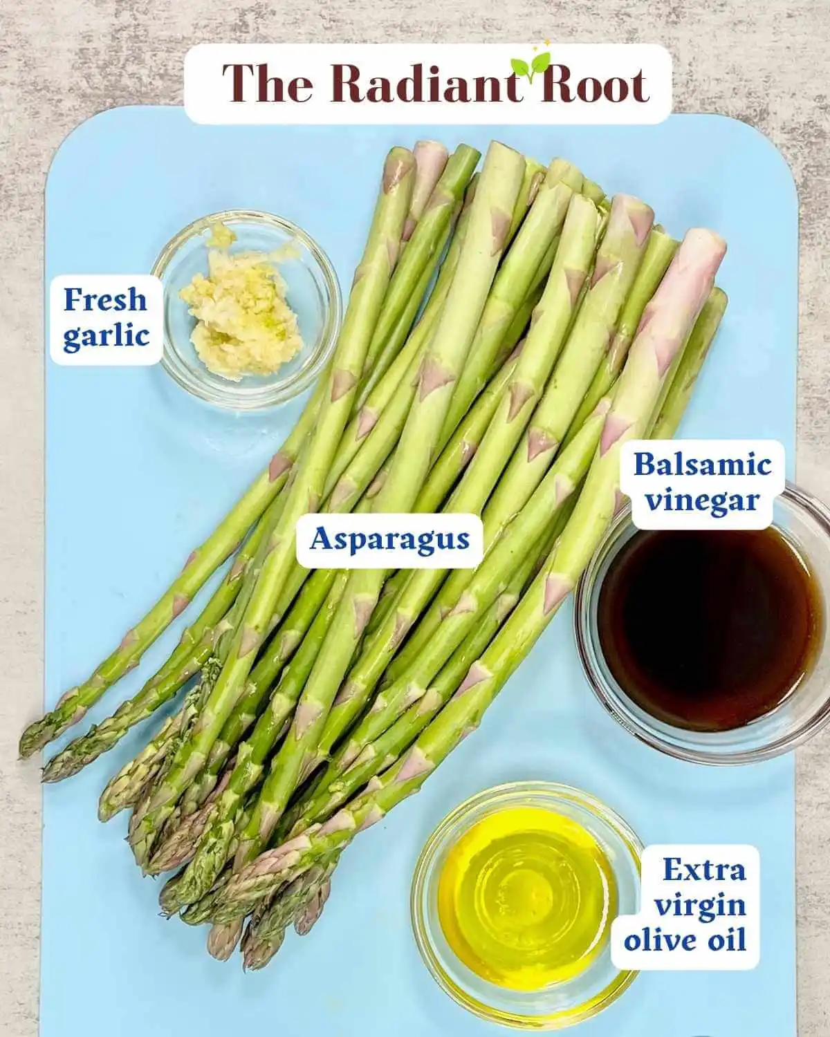 Balsamic glazed asparagus Ingredient photo: A marbled background containing a light blue cutting board with the ingredients for balsamic asparagus: a pound of fresh asparagus, on the left of that is a small clear glass dish with fresh diced garlic. Below the asparagus to the right is a small clear glass dish of extra virgin olive oil, and next to the aspargus in the middle of the photo is balsamic vinegar in small clear glass dish. The names of the ingredients are next to each ingredient | best roasted asparagus | The Radiant Root