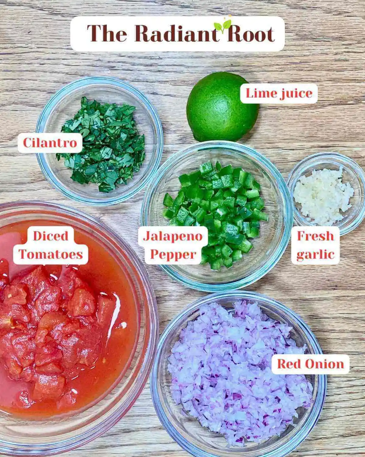 Cilantro salsa Ingredient Photo: A close-up of a wooden table containing the ingredients for salsa in various clear glass dishes: cilantro, lime juice, jalapeno pepper, fresh garlic, diced tomatoes, and red onion with the names next to them. | DIY salsa | The Radiant Root