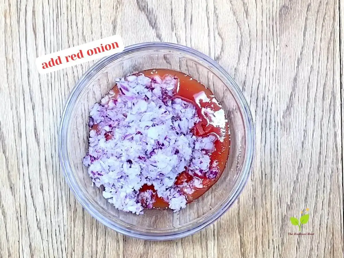 Cilantro salsa recipe instruction photo 2 of 8: A close-up of a wooden table containing a medium glass mixing bowl containing diced canned tomatoes and diced red onion. It reads “Add red onion.” best homemade salsa | The Radiant Root