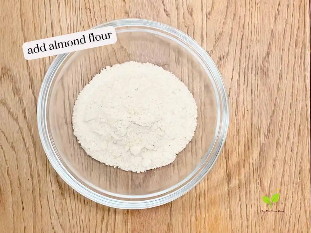 GF Chicken Wings recipe instruction photo 4 of 14 : A wooden table containing a large mixing bowl containing almond flour. It reads “add almond flour.” | use almond flour | The Radiant Root