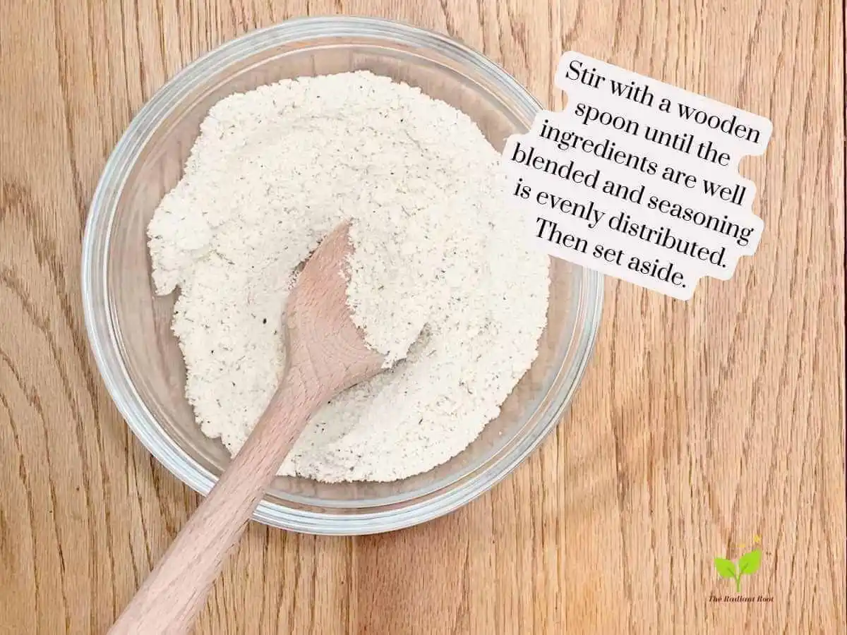 GF Chicken Wings recipe instruction photo 7 of 14 : A wooden table containing a large mixing bowl containing almond flour, garlic powder, and Italian seasoning mixed with a wooden spoon sitting in the bowl. It reads “stir with a wooden spoon until the ingredents are well blended and seasoning is evenly distributed. Then set aside.” | What is blanched almond flour | The Radiant Root