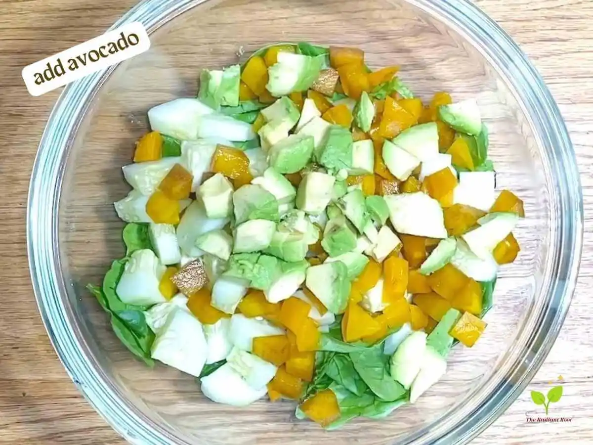 Golden Beet Salad recipe instruction photo 8 of 11 : A wooden table with a close up of a clear medium mixing bowl containing spinach, cucumbers, beets, and cucumber. In the upper left corner it reads “Add avocado.” | benefits of gold beets | The Radiant Root