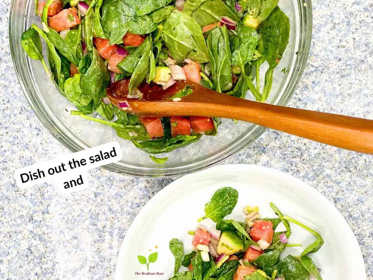 Watermelon avocado salad recipe instruction photo 19 of 20: There is a black speckled table top with two bowls. One is a large clear glass mixing bowl. Inside the bowl is spinach, watermelon, red onion, and avocado tossed with dressing. Sitting in the bowl are salad tongs. Below that is a large white salad bowl containing the finished salad. In the upper left corner it reads “Dish out the salad and.” | watermelon delivery | The Radiant Root