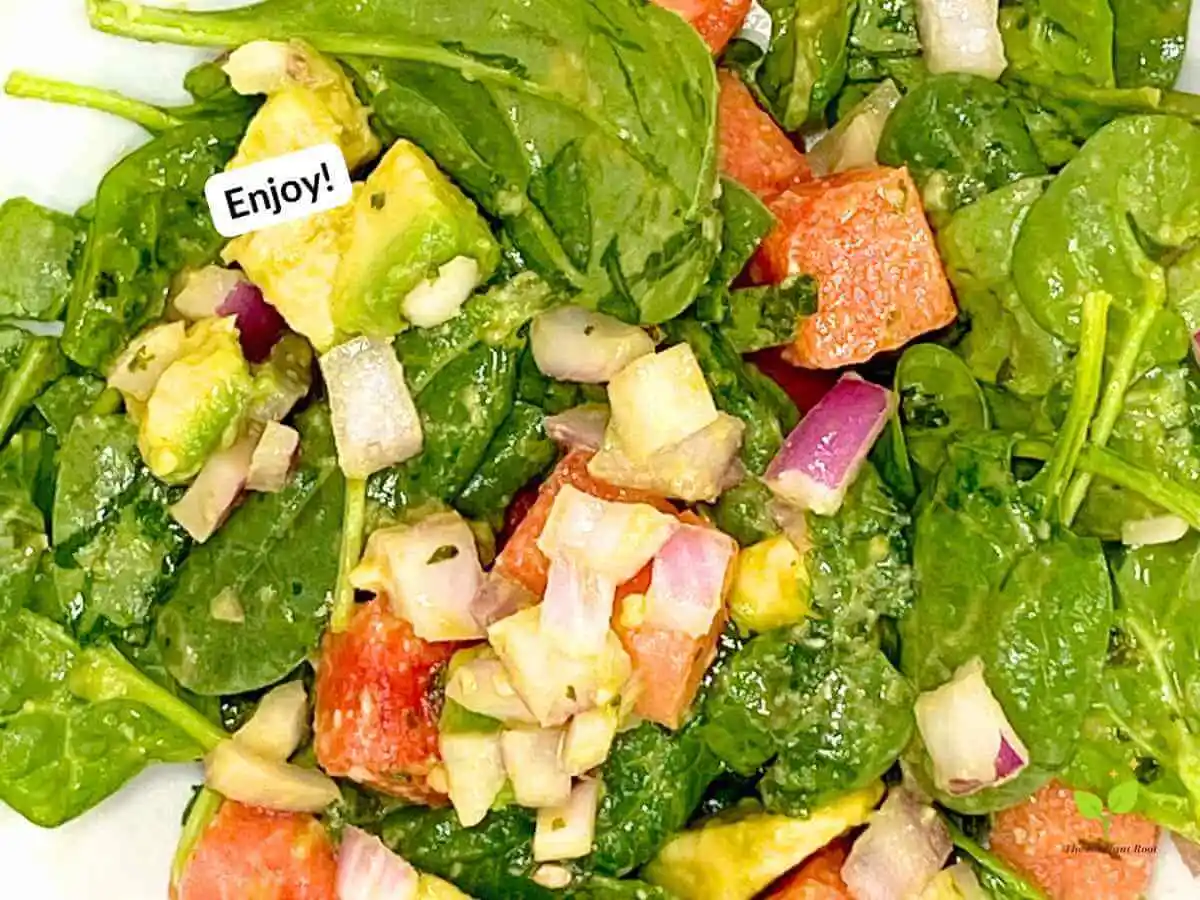 Watermelon avocado salad recipe instruction photo 20 of 20: A close up of a white large salad bowl with a finished salad containing spinach, watermelon, avocado, and red onion tossed with a dressing containing extra virgin olive oil, cilantro, and lime juice. In the upper left corner it reads “enjoy!” | how long does cut watermelon last | The Radiant Root