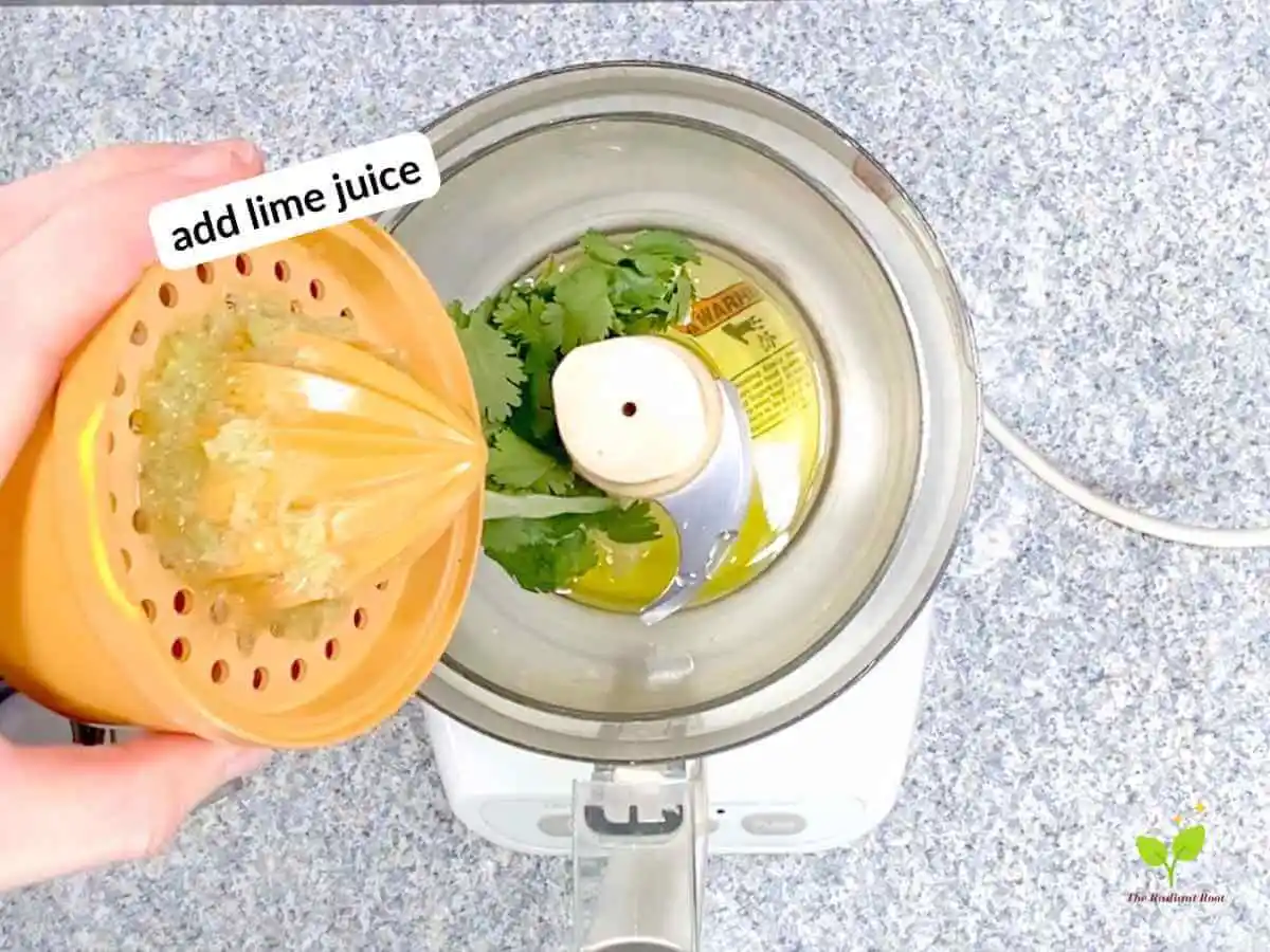 Watermelon avocado salad recipe instruction photo 5 of 20: There is a black speckled table top with a food processor with the food processor bowl on top of it. The lid is on the table next to it. In the food processor bowl is extra virgin olive oil and cilantro. There is a hand pouring lime juice into the bowl. In the upper left hand corner it reads “add lime juice.” | Is watermelon good for you | The Radiant Root